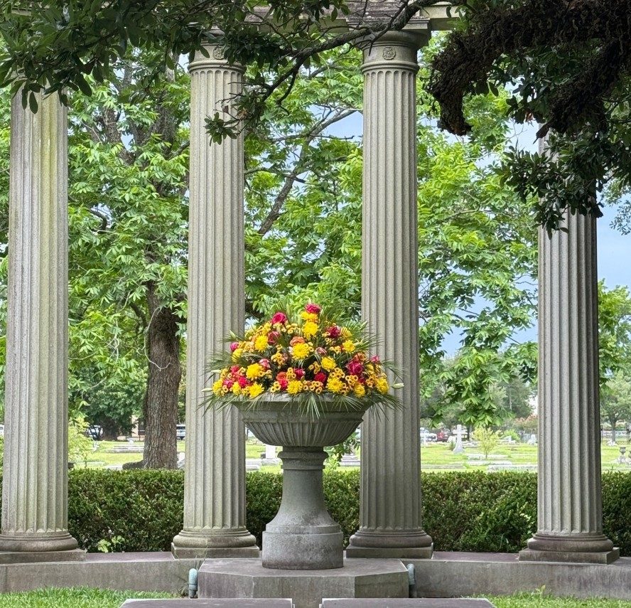 Stone urn of yellow and red flowers standing among fluted columns at Magnolia Cemetery
