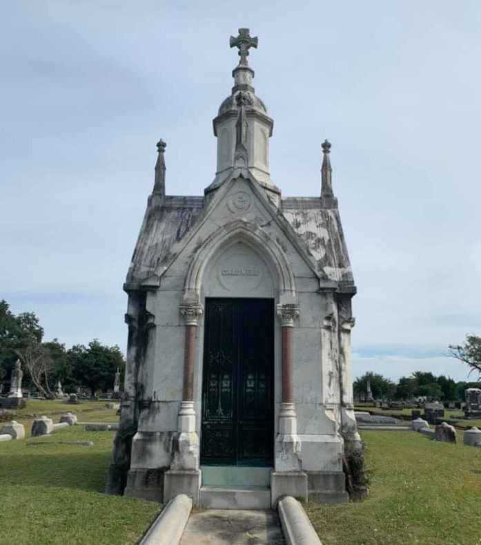 Gothic revival family mausoleum topped with a stone cross at Magnolia Cemetery