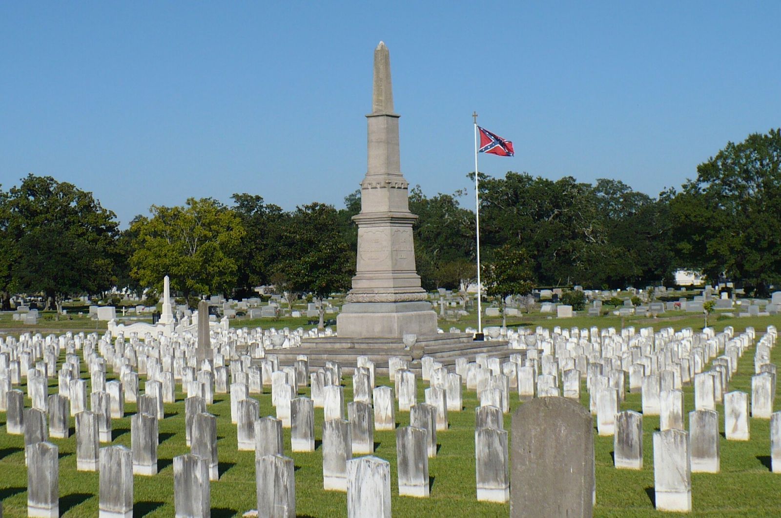Rows of veterans&rsquo; headstones surrounding a stone obelisk at Magnolia Cemetery