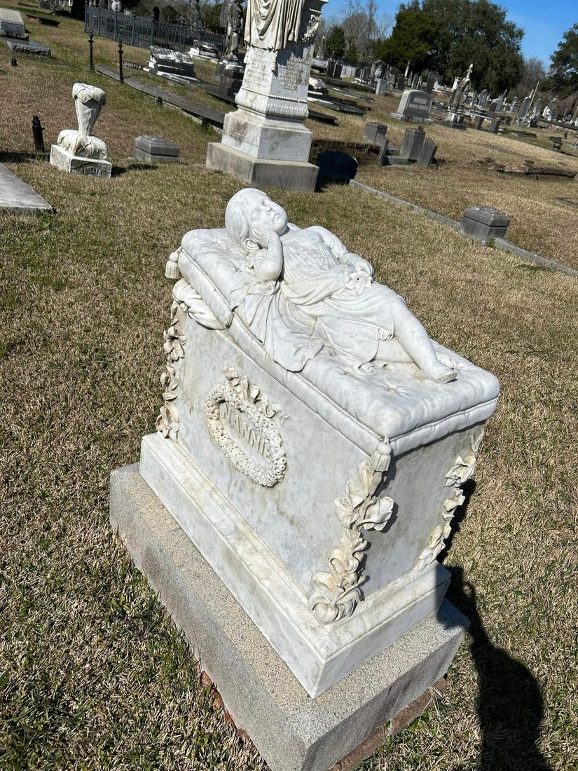 Marble effigy of a sleeping infant resting on a tasseled pillow atop the Mannie monument